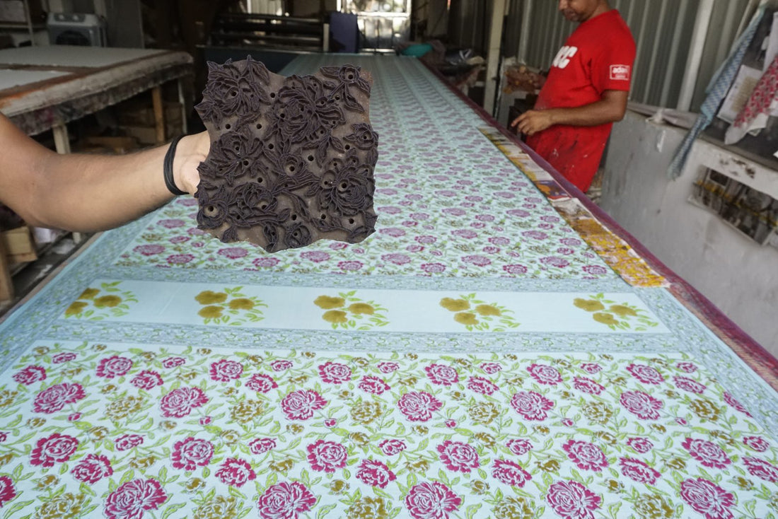 Artisan holding a carved teak printing block over hand block printed fabric | Myyra Jaipur