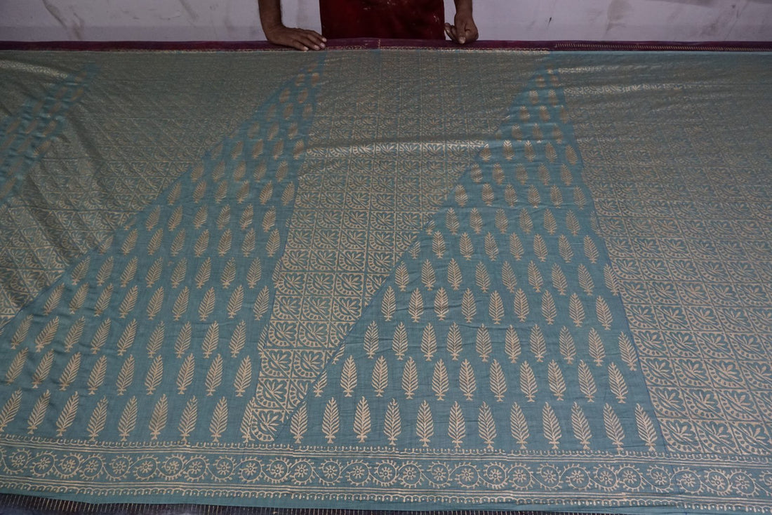 Artisan hands laying out gold hand block printed fabric in the Myyra Jaipur workshop