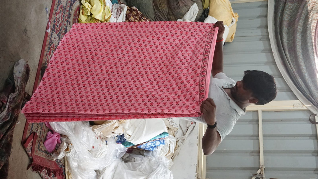 Artisan holding folded pink hand block printed organic cotton fabric | Myyra Jaipur
