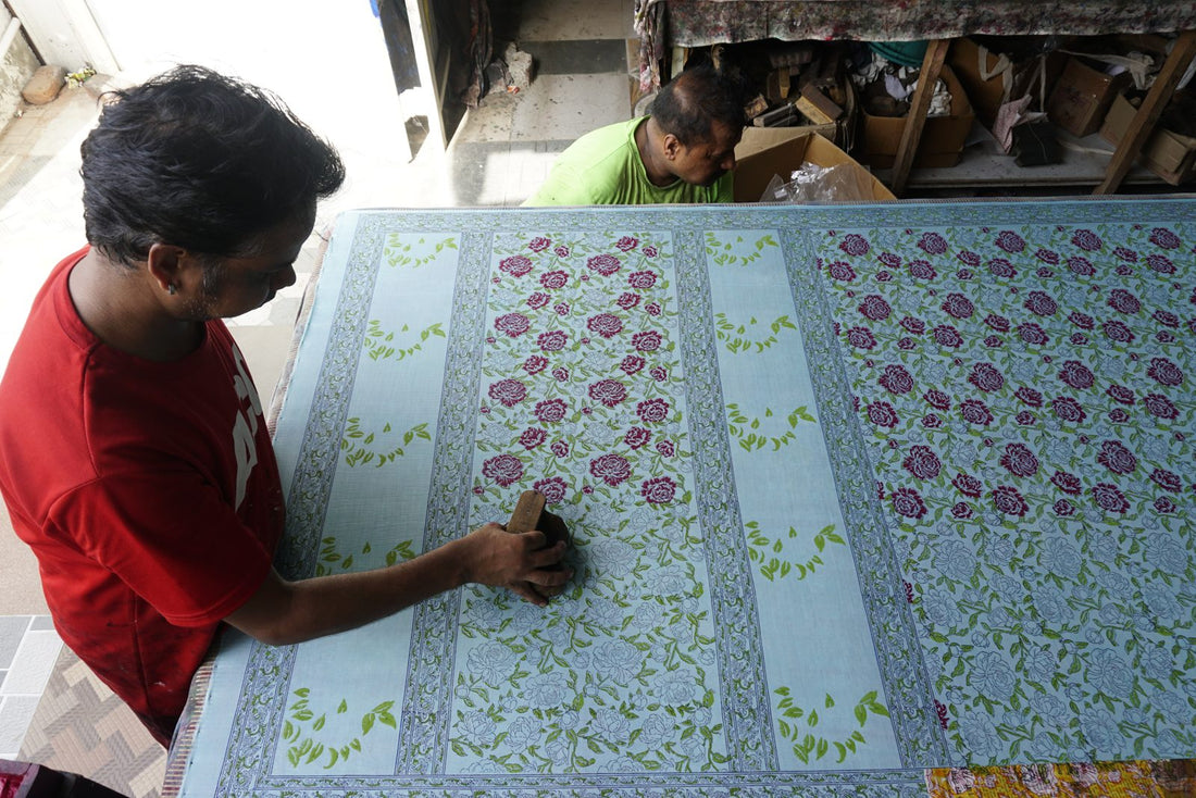 Two Myyra artisans hand block printing a floral textile in the Jaipur workshop